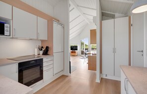 A modern kitchen with white cabinetry, a built-in oven, and a dining area with a table and chairs. - Cozy home in Vejers Strand with sauna (Vejers Strand)