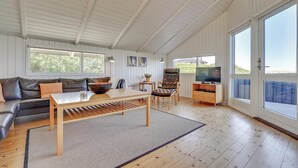 Un salon spacieux avec un plancher en bois, un canapé, une table à manger et un téléviseur.