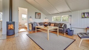 Un salon chaleureux avec un poêle à bois, un canapé, une table basse et un tapis.