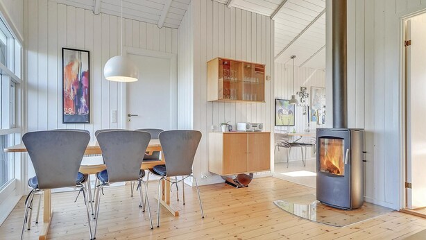 Un salon moderne avec un plancher en bois, une table à manger avec des chaises, une cheminée et un coin cuisine équipé de placards et d’une cuisinière.