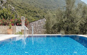 Una piscina amb una paret de pedra i un paisatge de muntanyes de fons.