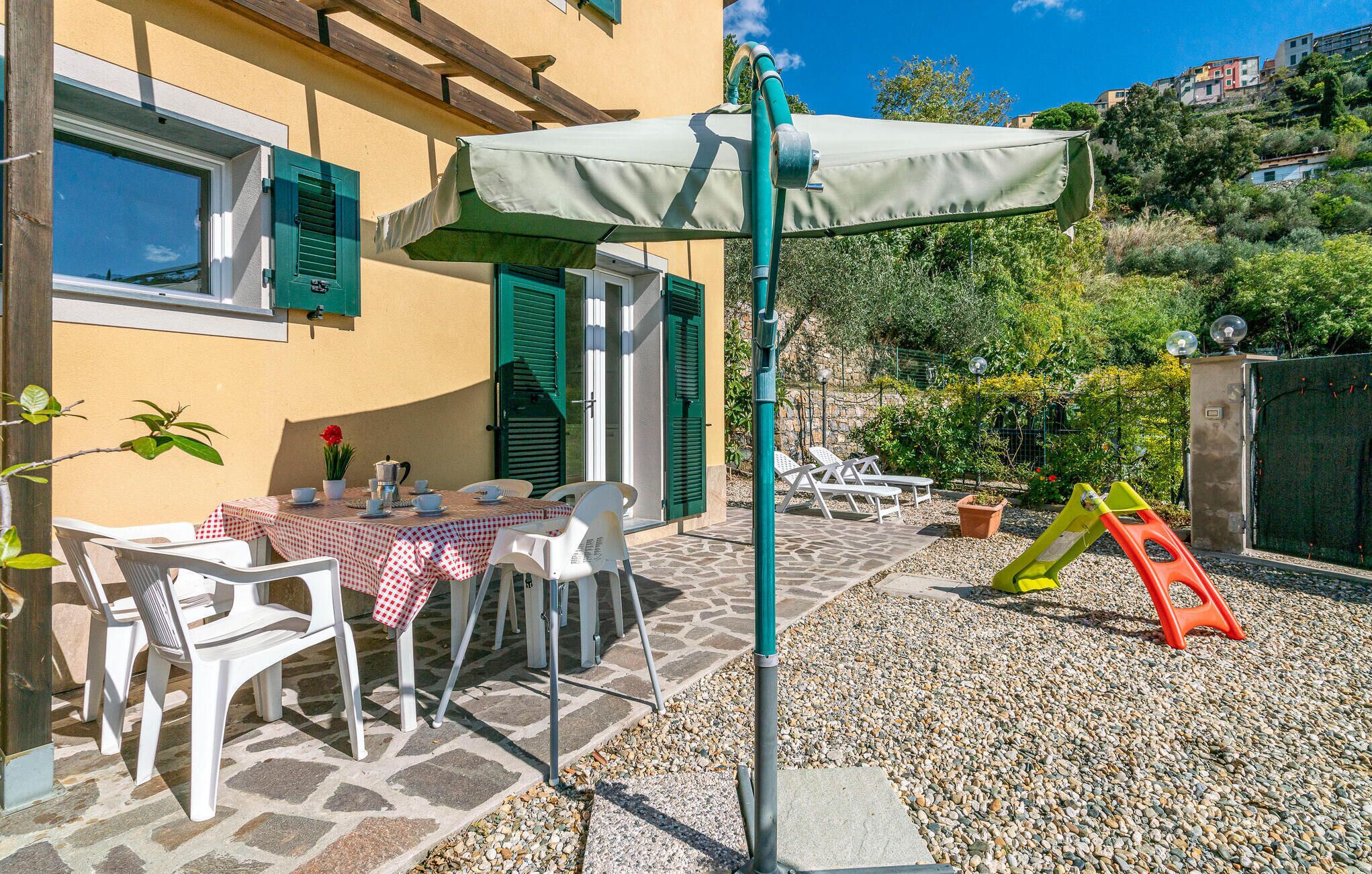 A patio with a table set for two, outdoor chairs, and a children's play area with a slide.