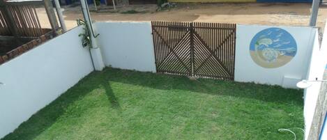 A white car parked in a grassy area with a gated entrance and a wall with a circular design.