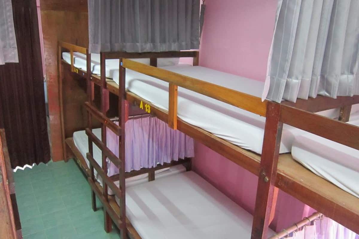 A bunk bed room with a wooden frame, a pink wall, and a green floor.