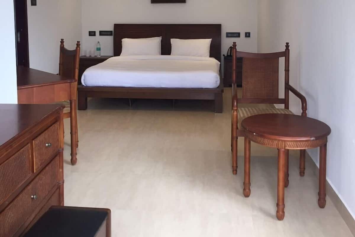 A bedroom with a large bed, wooden furniture, a painting on the wall, and a small table.