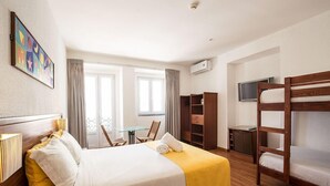Une chambre d’hôtel avec un lit, un bureau, une télévision et un lit superposé.