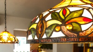 Un coin repas agrémenté d’un lustre suspendu aux vitraux, d’une plante en pot et d’un tapis en peau de vache.