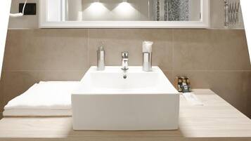 A bathroom with a white sink, two faucets, a mirror, and a towel on the counter.