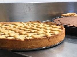 Piirakka, jonka päällä on koristeellinen ritilänmuotoinen kuori, ja se on asetettu metalliselle tarjottimelle.