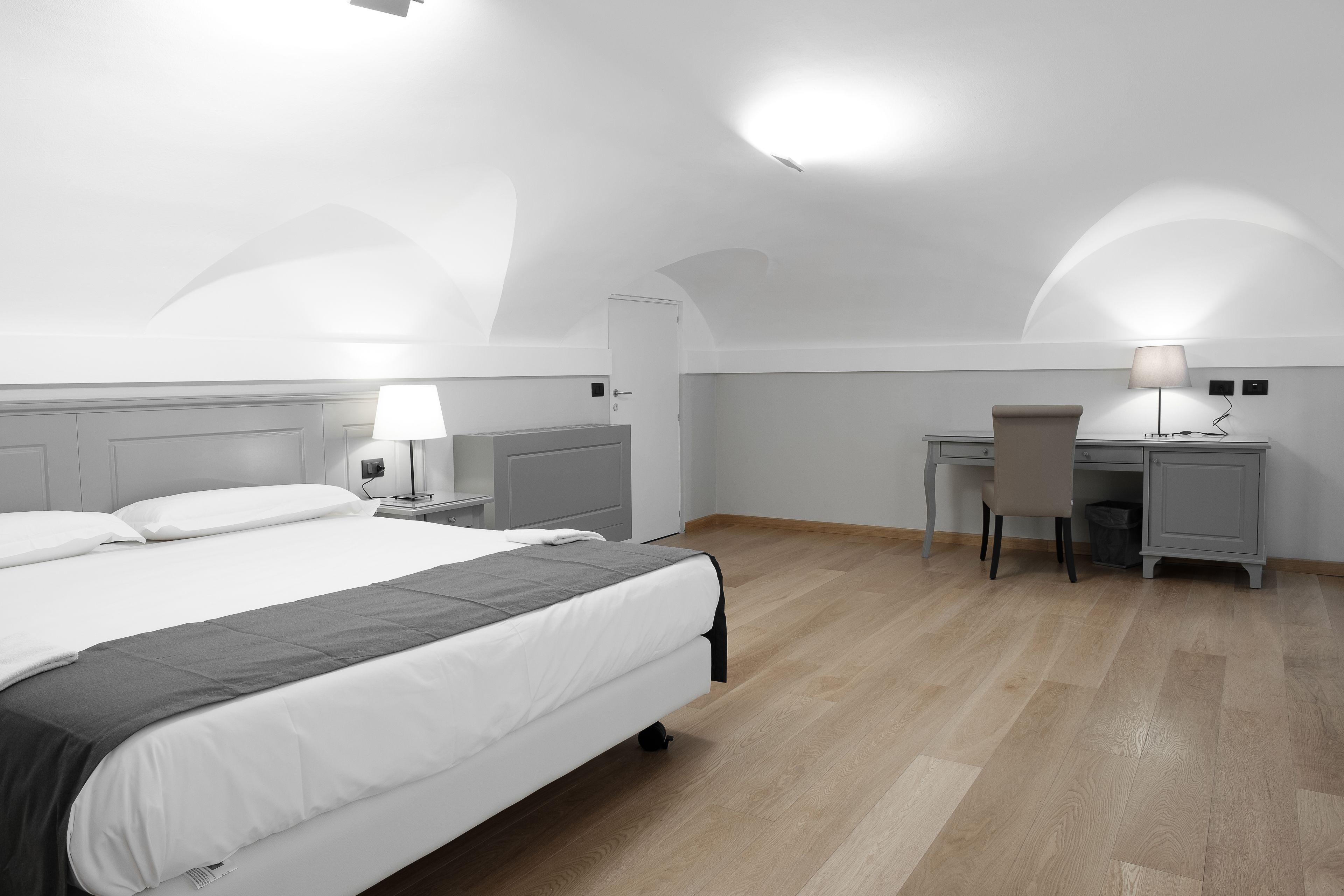A modern hotel room with a large bed, a desk, and a chair.
