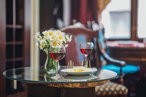 A dining table with a glass vase of white flowers, two wine glasses, and a plate with food and toothpicks. - Emigrant (Tbilisi)