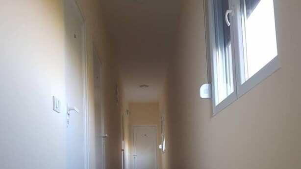 Un pasillo estrecho con suelo de baldosas y una ventana a la derecha.
