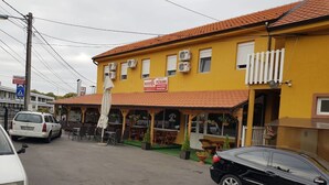 Un edificio amarillo con un letrero que indica que es un albergue. Hay áreas de estar al aire libre con mesas y sillas.
