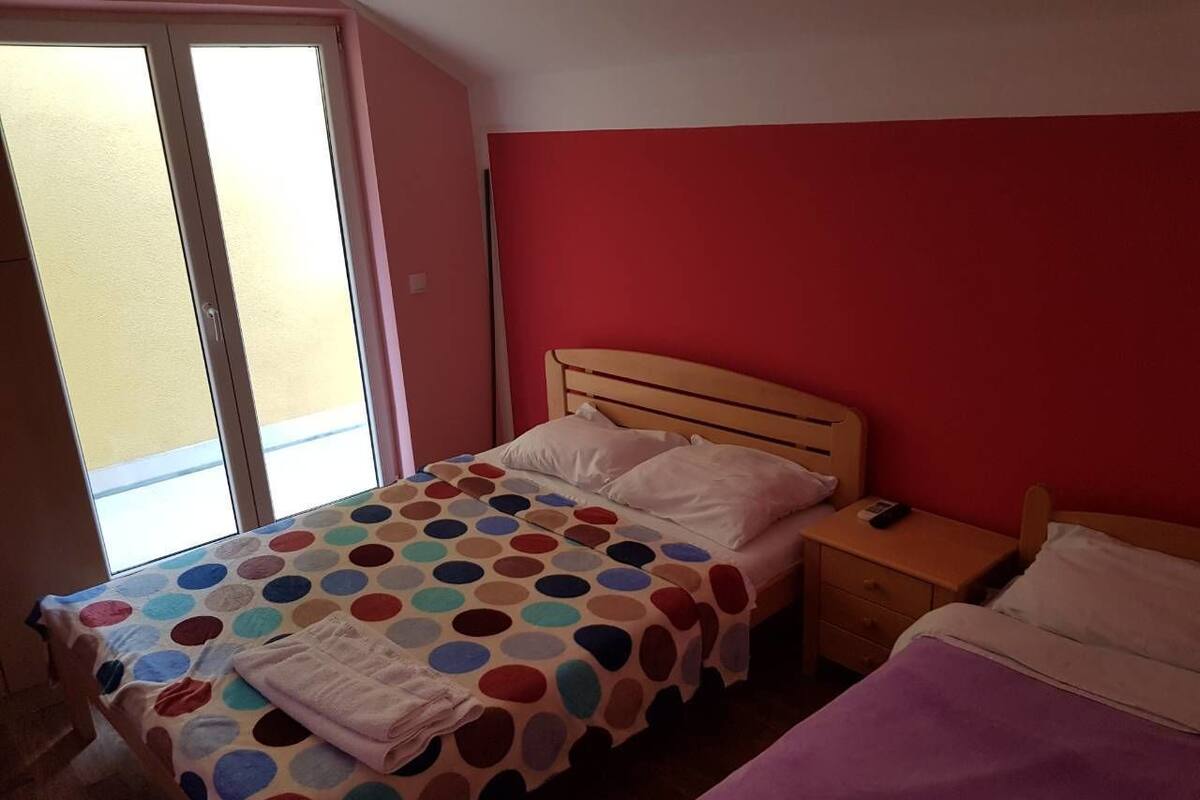 A bedroom with a bed, a nightstand, and a window.