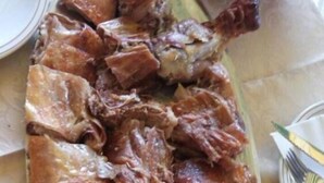 Un plato de carne en lonchas, probablemente cerdo, dispuesto sobre un plato ovalado verde.