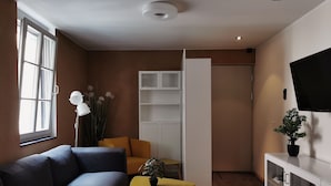 En moderne stue med en grå sofa, et gult sofabord og et hvidt skab med glasdøre.