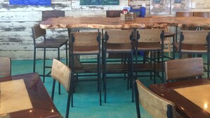 Interior de restaurante con paredes de madera, una larga mesa de madera y varias sillas.