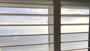 Habitación con vista a la playa a través de persianas.