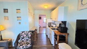 A compact living space with a kitchenette, a dining area with a table and chairs, and a TV.