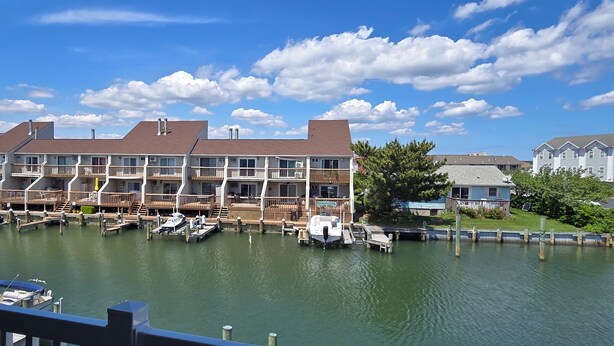 A waterfront property with multiple balconies, a dock with boats, and a clear blue sky.