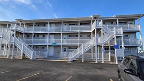 A multi-story motel with a central staircase and a parking lot in front.