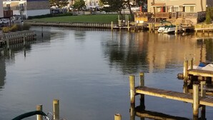 A marina with docked boats, a wooden pier, and a residential building in the background.