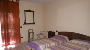 Une chambre avec deux lits, un miroir, une petite table et une chaise.