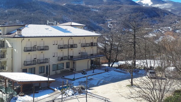 Un hôtel doté de nombreux balcons, d’un espace extérieur couvert et offrant une vue sur des montagnes enneigées.