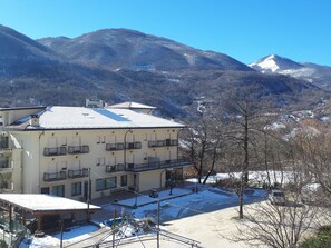 Un hotel con varios balcones, un área exterior techada y vistas a montañas nevadas.