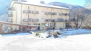 Un hôtel doté de nombreux balcons, d’une entrée couverte et offrant une vue sur des montagnes enneigées.