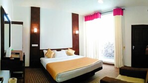Ein Hotelzimmer mit Bett, Schreibtisch, Stuhl und einem fensterbepflanzten Fenster.