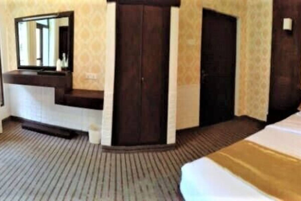 A hotel room with two beds, a sofa bed, a TV, and a mirror.