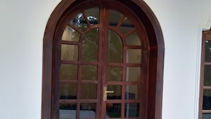 Eine hölzerne Doppeltür mit Fensterglas, eingebaut in eine weiße Wand mit einem kleinen Fenster zur Rechten.