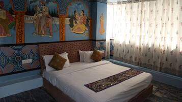 Un dormitorio con una cama grande, decoración en la pared y un ventanal con cortinas.