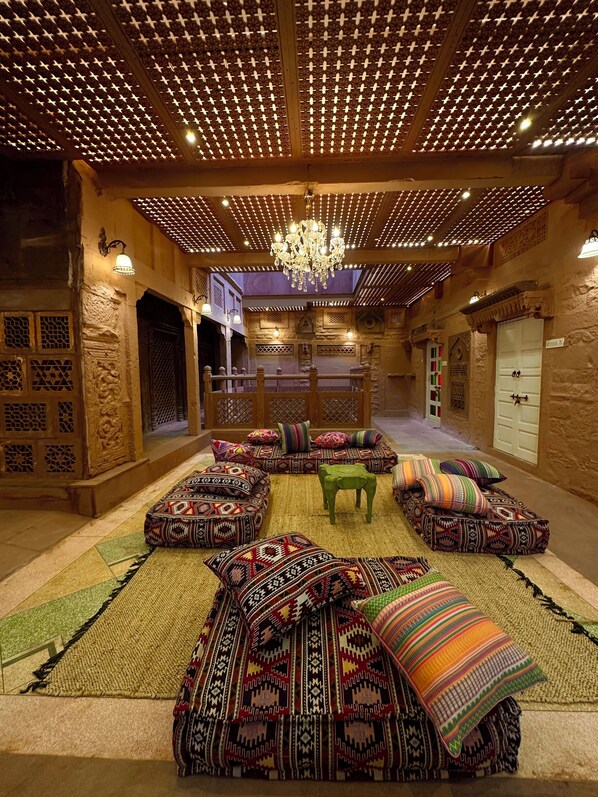 A traditional interior with patterned cushions, a chandelier, and a wooden ceiling.