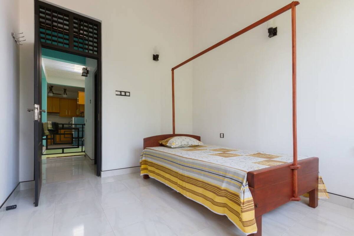 Un dormitorio con cama con dosel, suelo de madera y vista al área de la cocina.