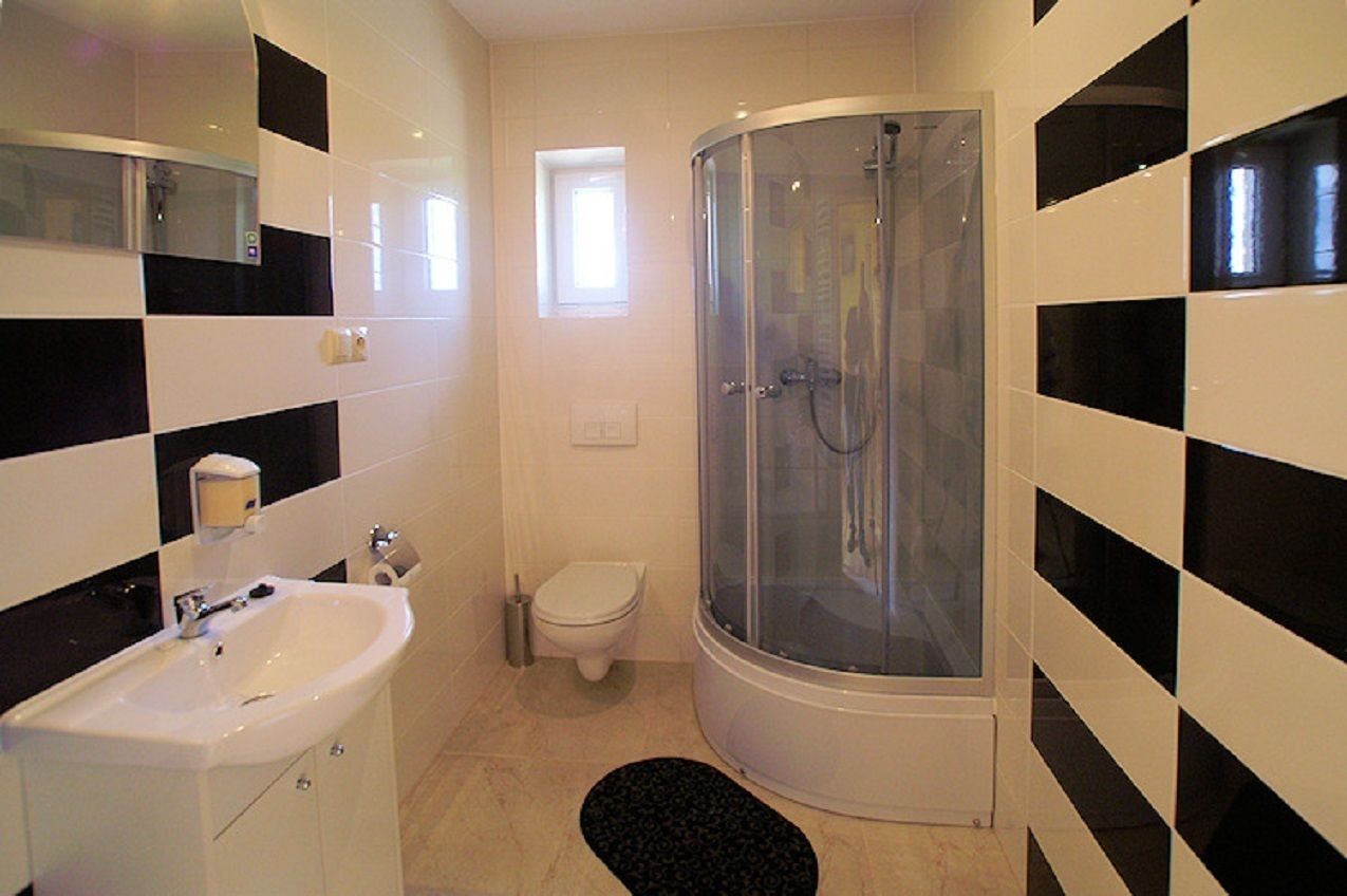 Une salle de bain avec un lavabo blanc, des toilettes et une douche fermée par des parois en verre.