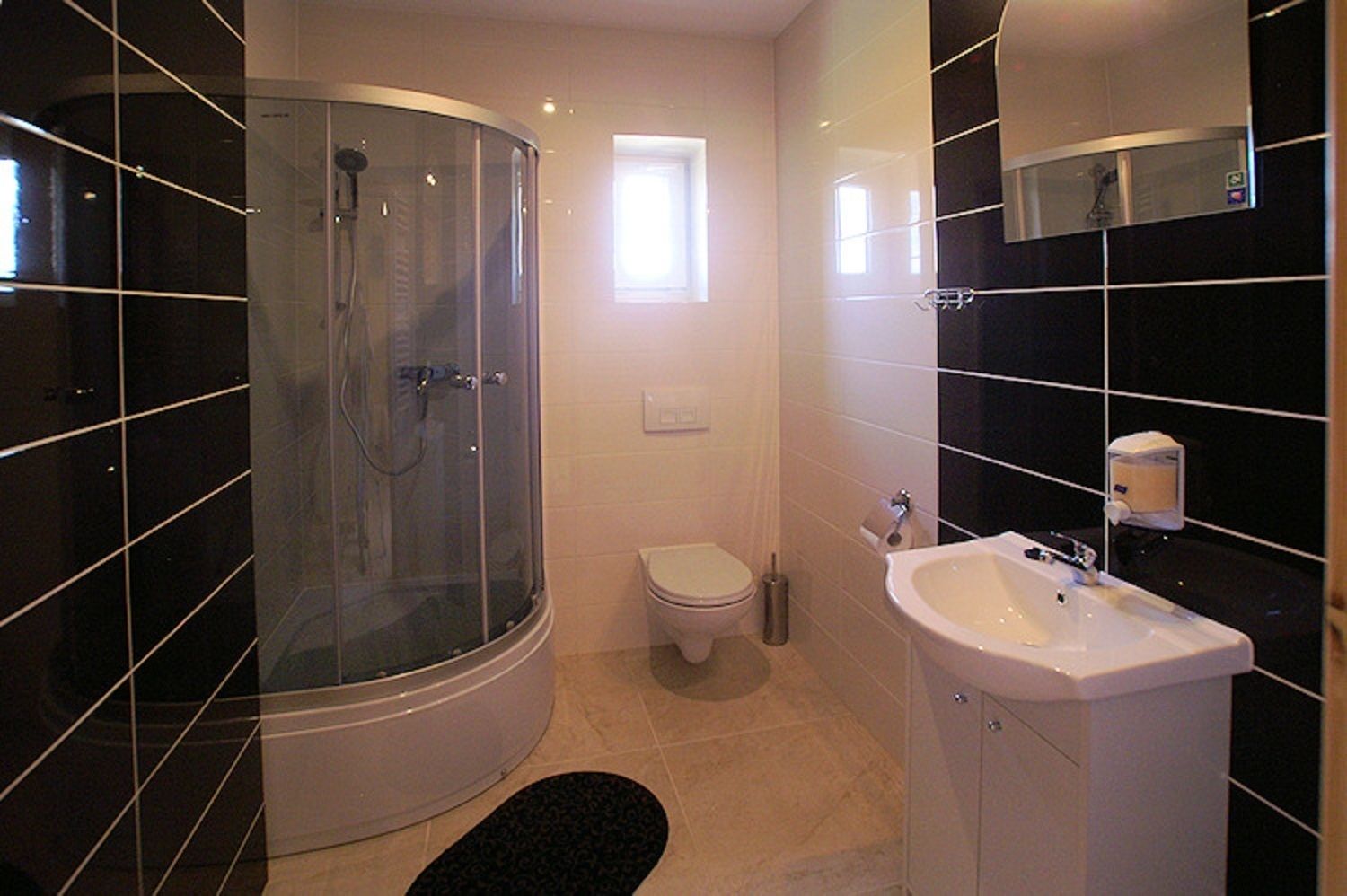 Een moderne badkamer met een glazen douchecabine, een toilet en een wastafel.