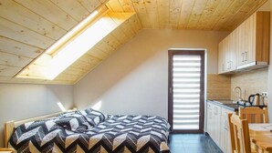 Un dormitorio pequeño con cama, una mesita y una kitchenette.