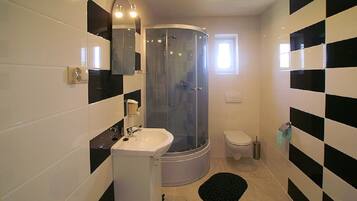 Un baño moderno con ducha de vidrio, lavamanos e inodoro.