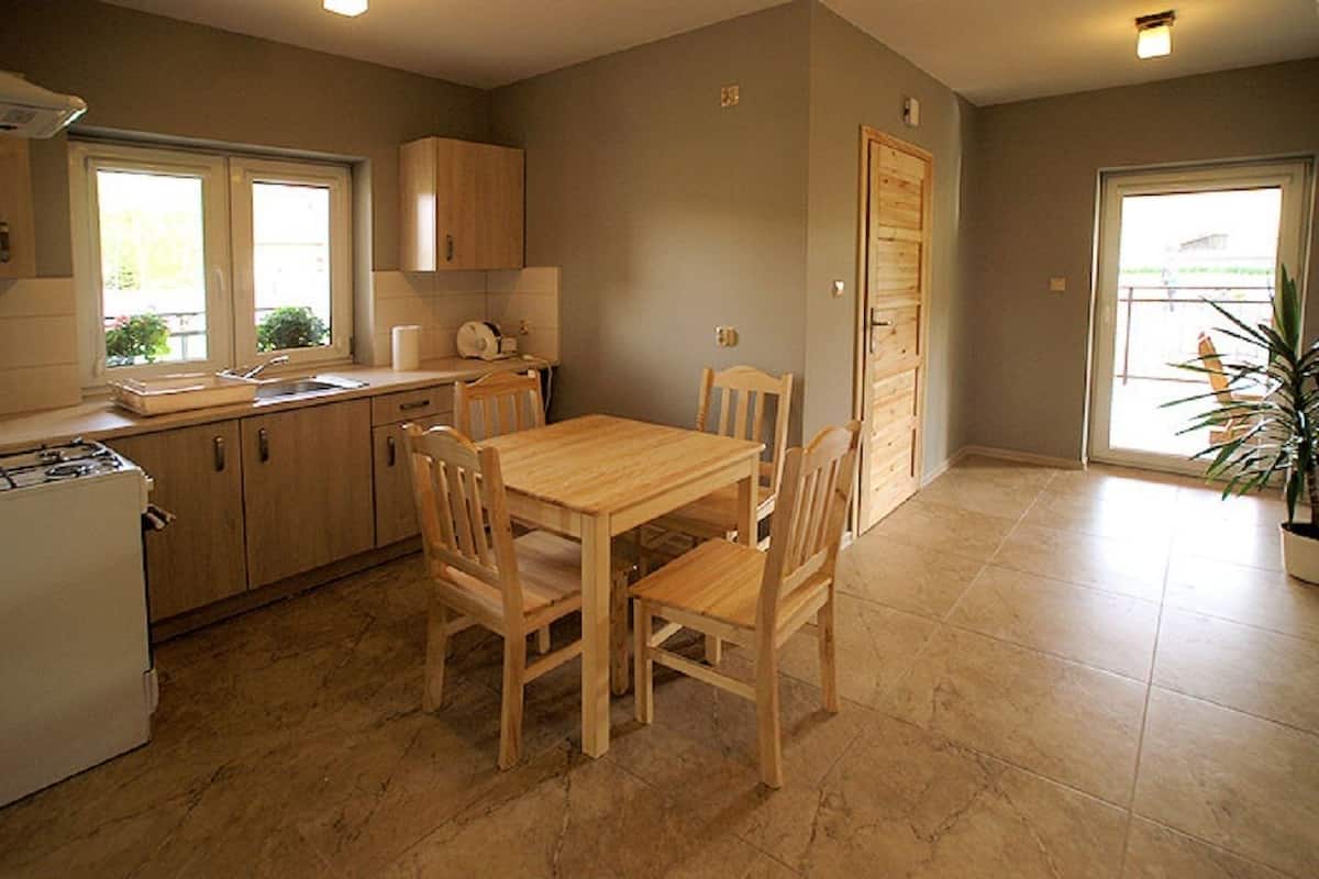 Una cocina con armarios de madera, una mesa de comedor con sillas y una planta en maceta.