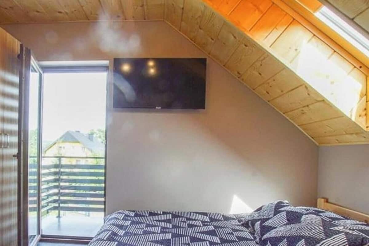 Un dormitorio con cama, televisión y vistas a una terraza de madera.