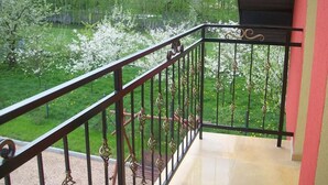 Un balcón con barandilla de metal que da a un jardín con árboles en flor.