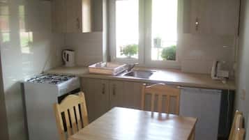 A compact kitchen with a gas stove, a sink, and a window.