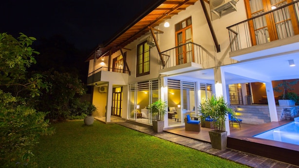 Une maison à deux étages dotée d’un balcon, d’une piscine et d’un espace extérieur bien éclairé.