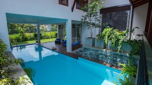 Une piscine dotée d’une terrasse carrelée, entourée de plantes en pot et de meubles de jardin.