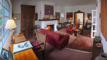 Un salón tradicional con chimenea, sofás rojos y una variedad de adornos decorativos.
