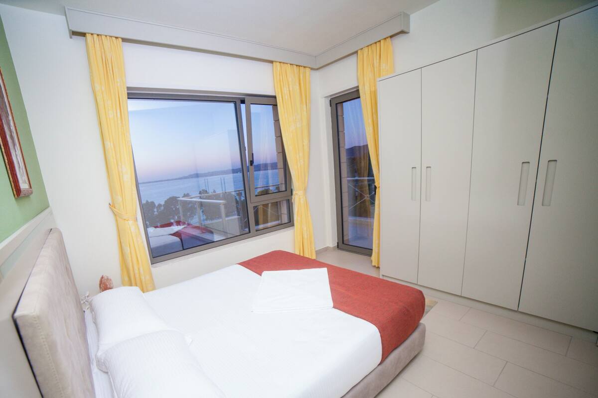 Une chambre d’hôtel avec un lit, une armoire et une vue sur la mer par la fenêtre.