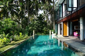 A swimming pool surrounded by lush greenery and modern architecture.