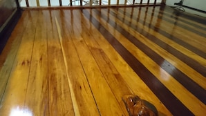 Een houten vloer met een leuning op de achtergrond.